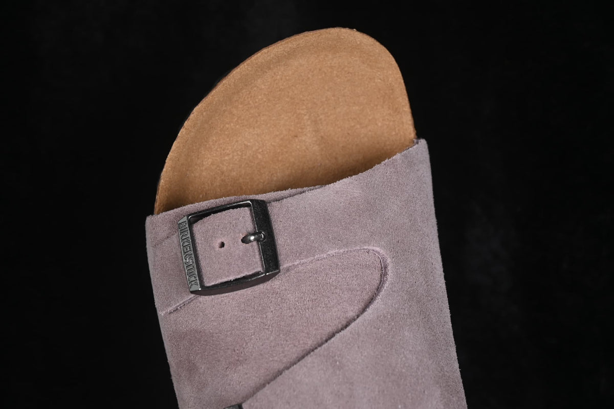 Close-up of an adjustable buckle and lavender suede upper.