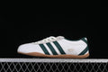 Side view of a white Adidas Tokyo sneaker with dark green stripes and a gum-colored sole