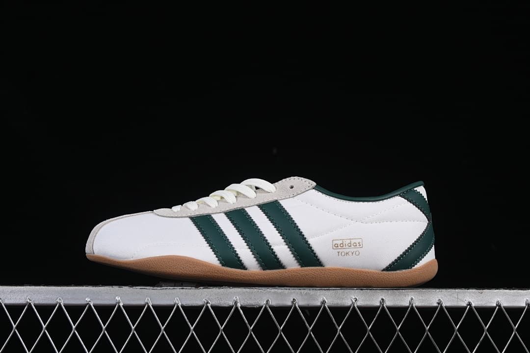 Side view of a white Adidas Tokyo sneaker with dark green stripes and a gum-colored sole