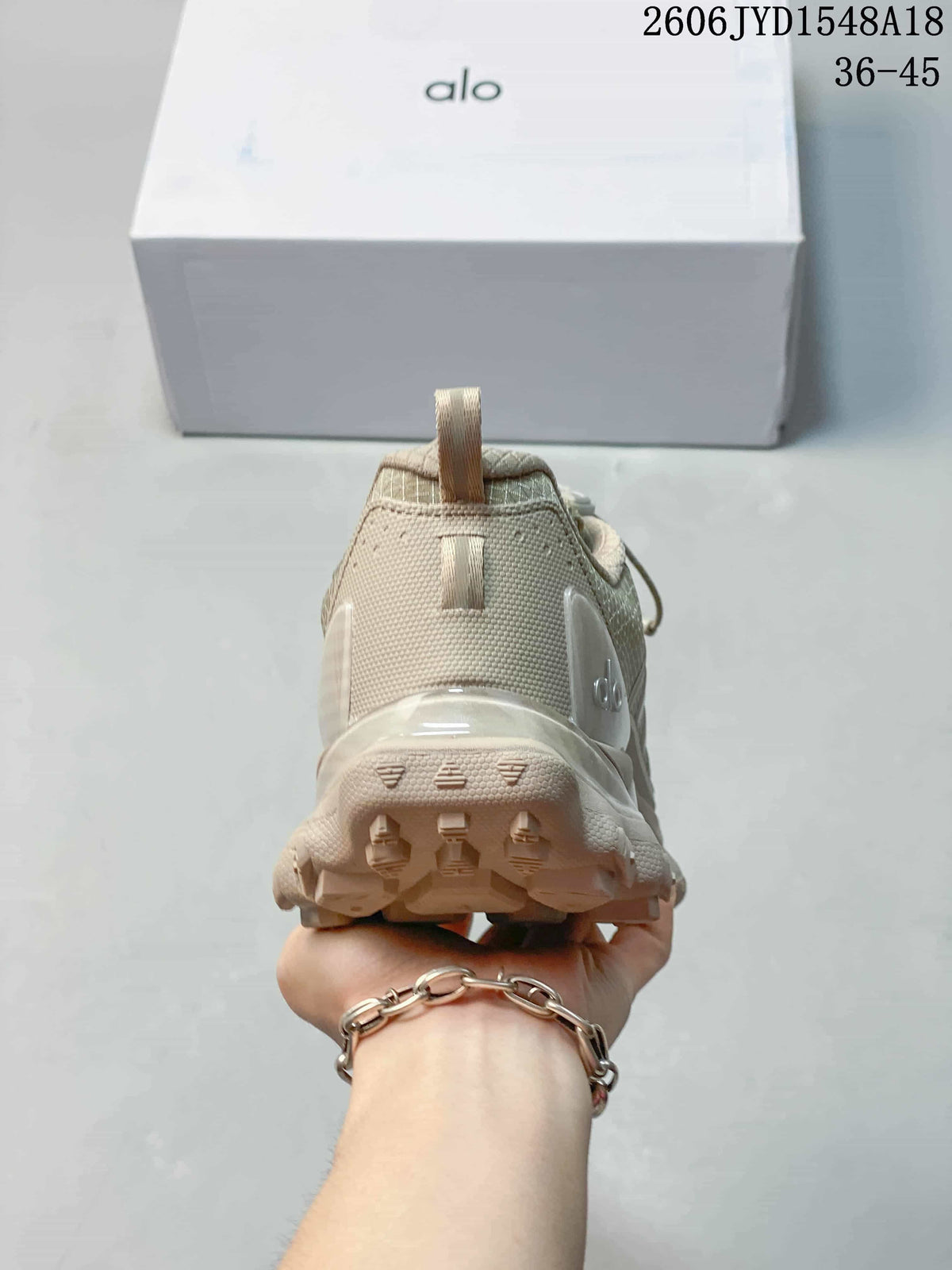 Rear view showing the heel and lugged outsole of a taupe trail shoe.
