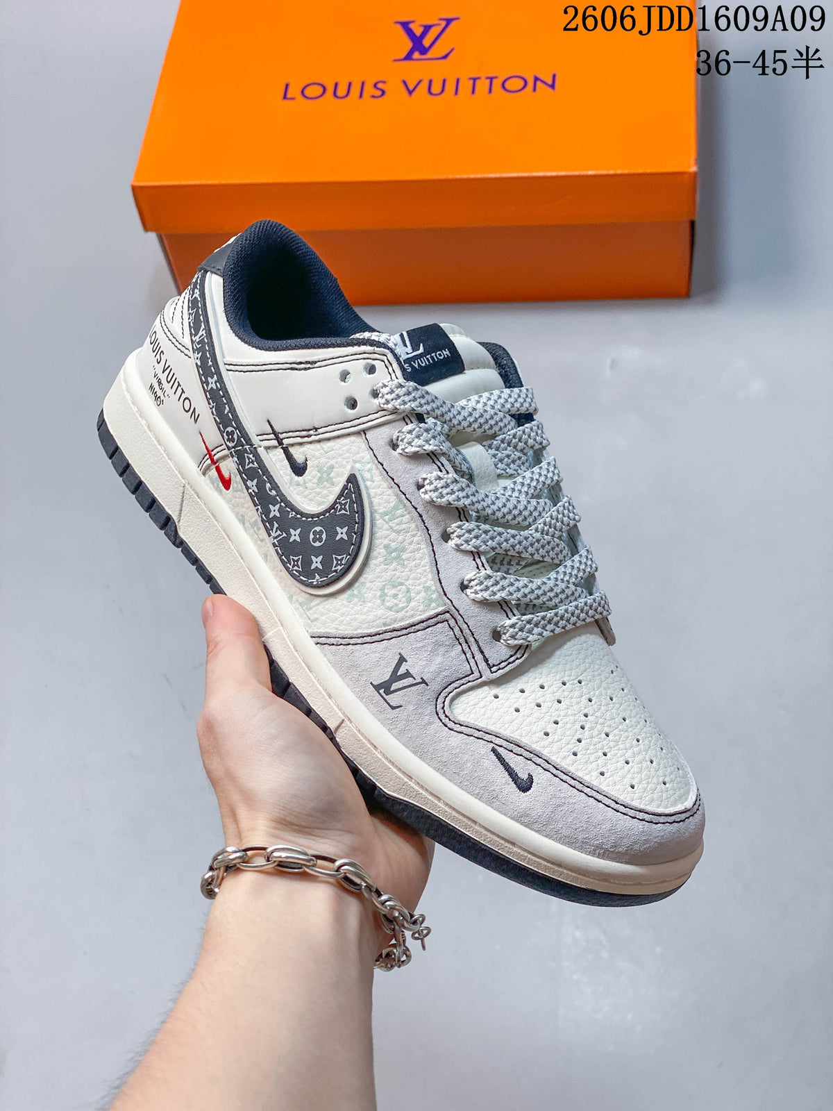 Gray and cream Nike SB Dunk Low sneaker with patterned graphic panels, shown in front of a branded orange box.
