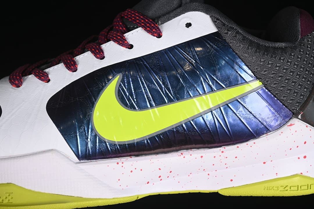 Close-up of the glossy navy side panel, yellow-green logo, white upper, and burgundy laces.