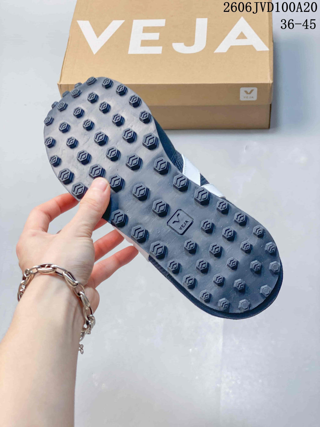Close-up of the textured outsole on a navy Veja sneaker, with a Veja box in the background.