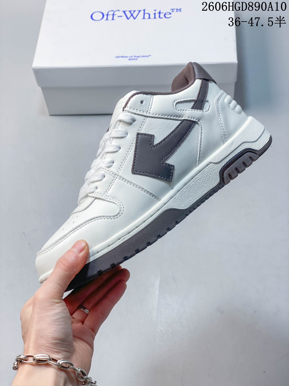 Side view of a white sneaker with a dark brown Arrow-style panel and contrasting outsole.