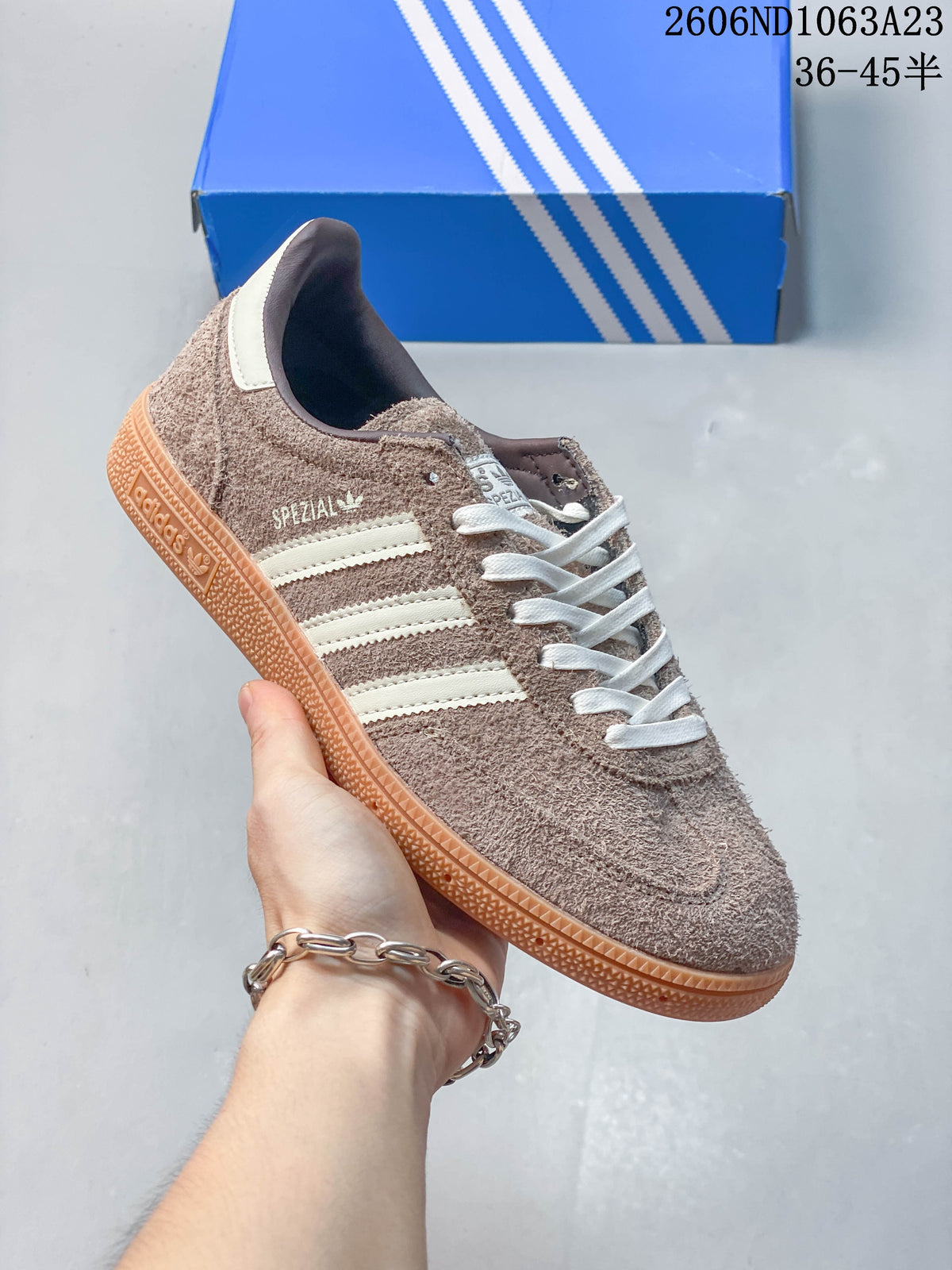 Angled side view showing the taupe textured upper, off-white stripes, and gum-colored sole.