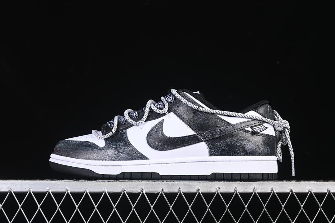 Side view of a black-and-white low-top sneaker with patterned laces and strap detail