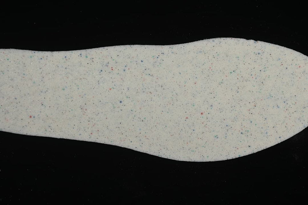 Removable shoe insole shown from above with a light speckled surface.