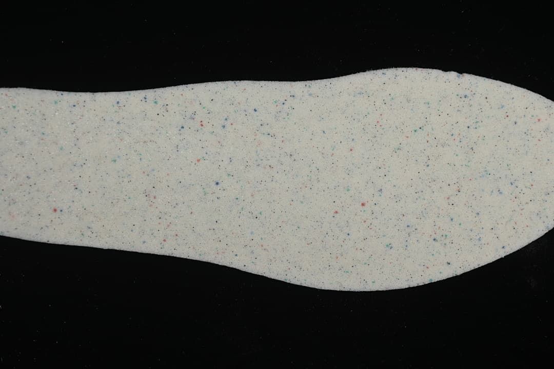 Removable shoe insole shown from above with a light speckled surface.