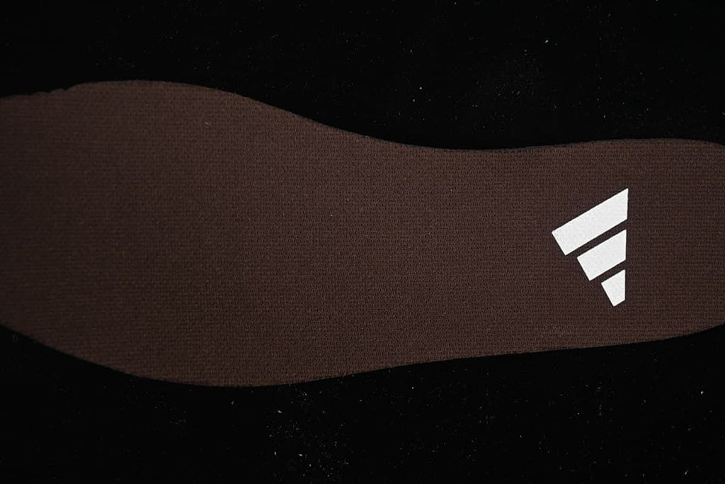 Close-up of the brown insole with a white three-stripe logo.
