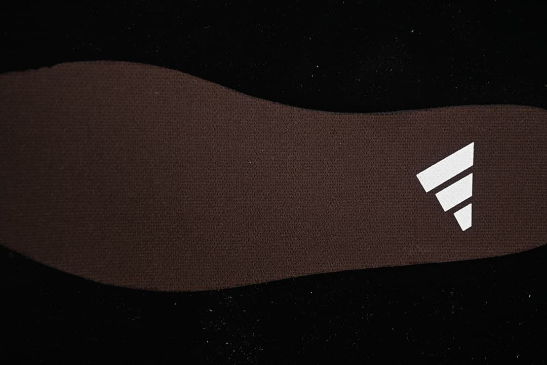 Close-up of the brown insole with a white three-stripe logo.