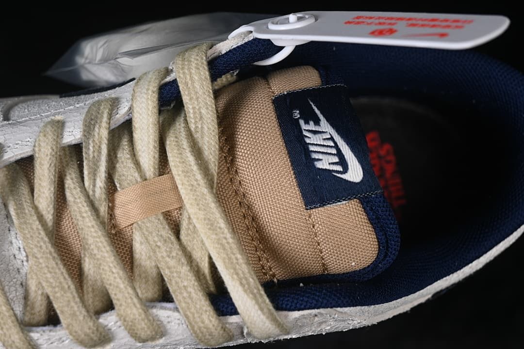 Close-up of cream laces, tan tongue, and navy Nike tongue label