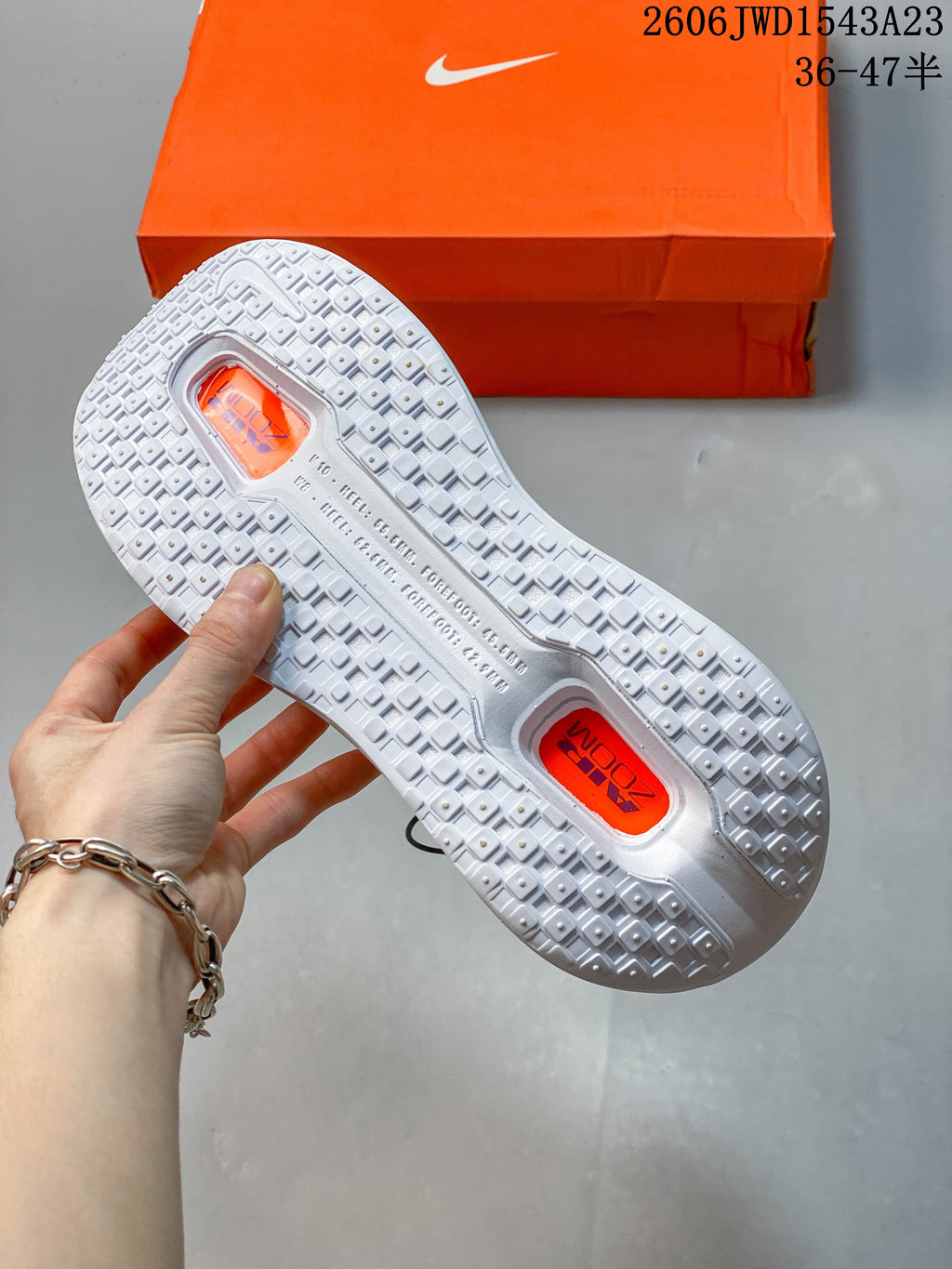 Underside of the white running shoe showing the patterned outsole and visible cushioning windows