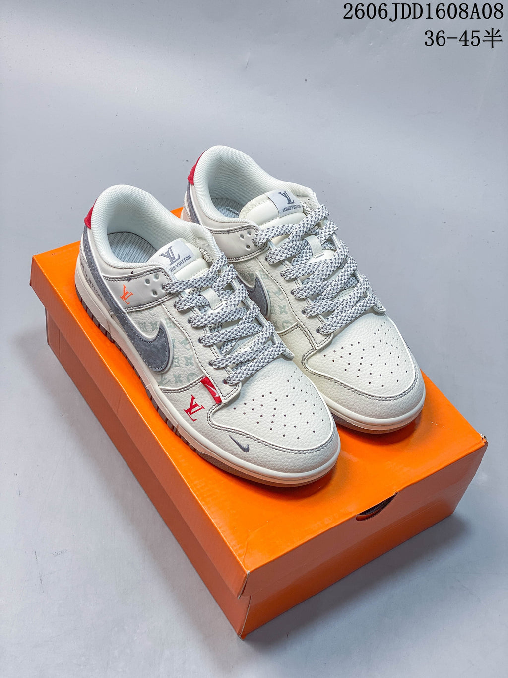 Pair of cream and gray patterned Nike SB Dunk Low sneakers displayed on an orange box