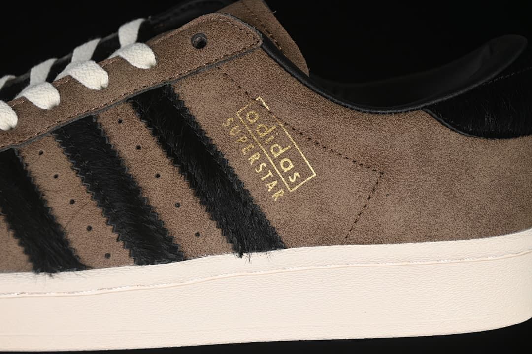 Close-up of black side stripes and gold-colored Superstar branding on the brown upper