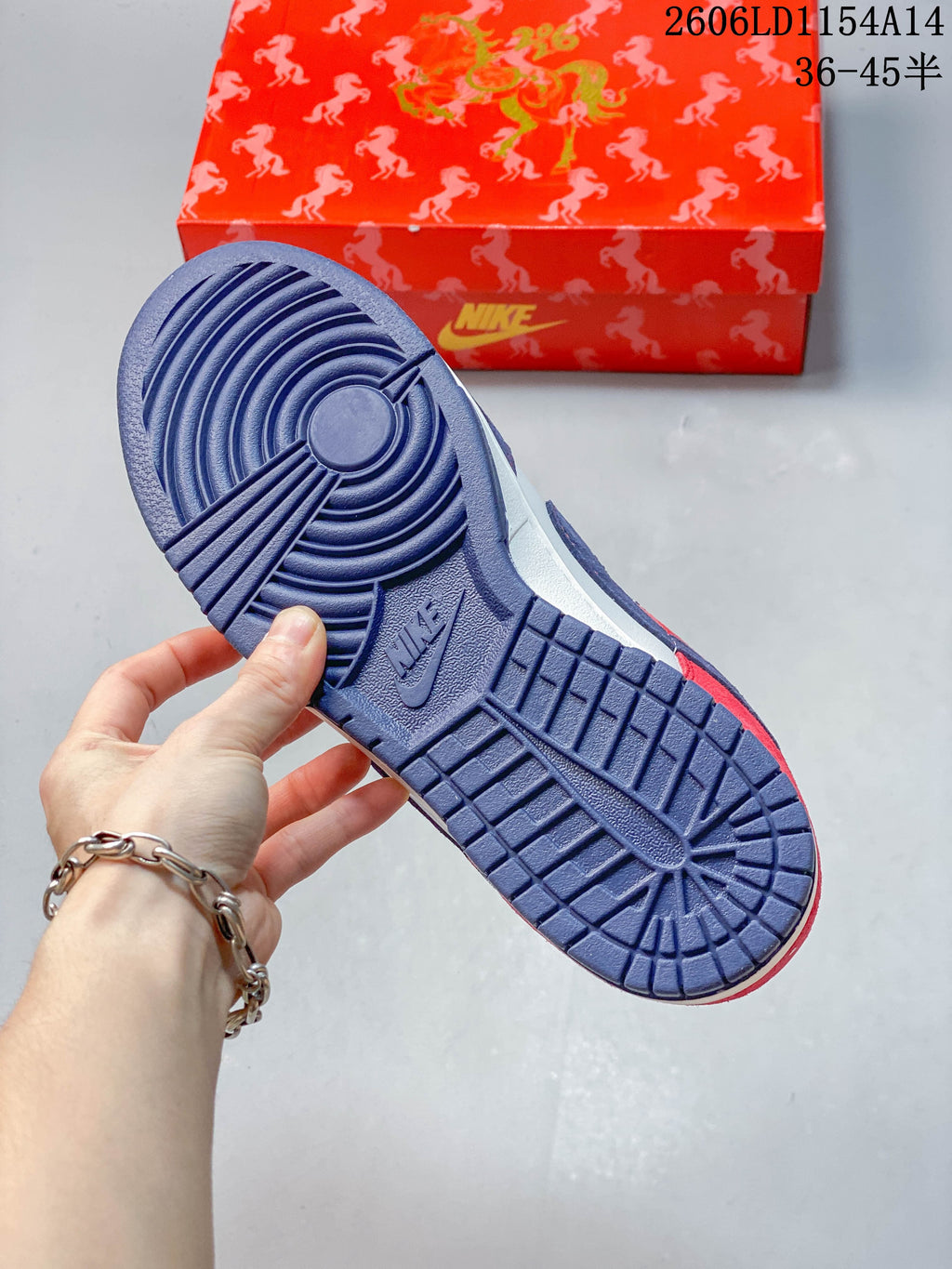 Blue outsole of a Nike SB Dunk Low sneaker with the patterned shoebox behind it