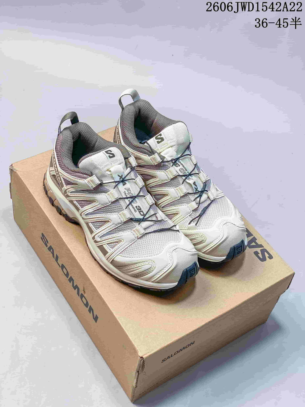 Pair of cream and gray Salomon XA Pro 3D trail sneakers on a branded shoebox