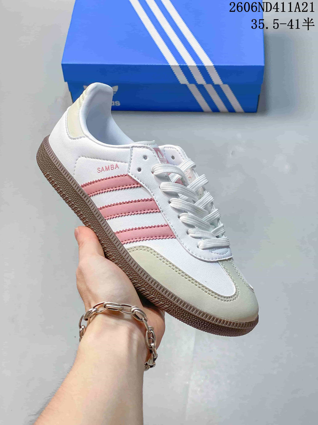 Close-up of a white sneaker with pink stripes, pale toe overlay, lace-up front, and gum-colored outsole.