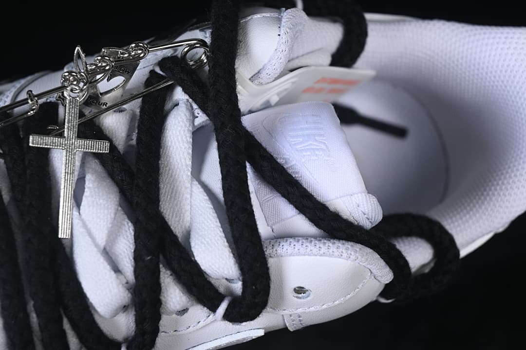 Close-up of the sneaker's black laces and a metal cross-shaped accessory.
