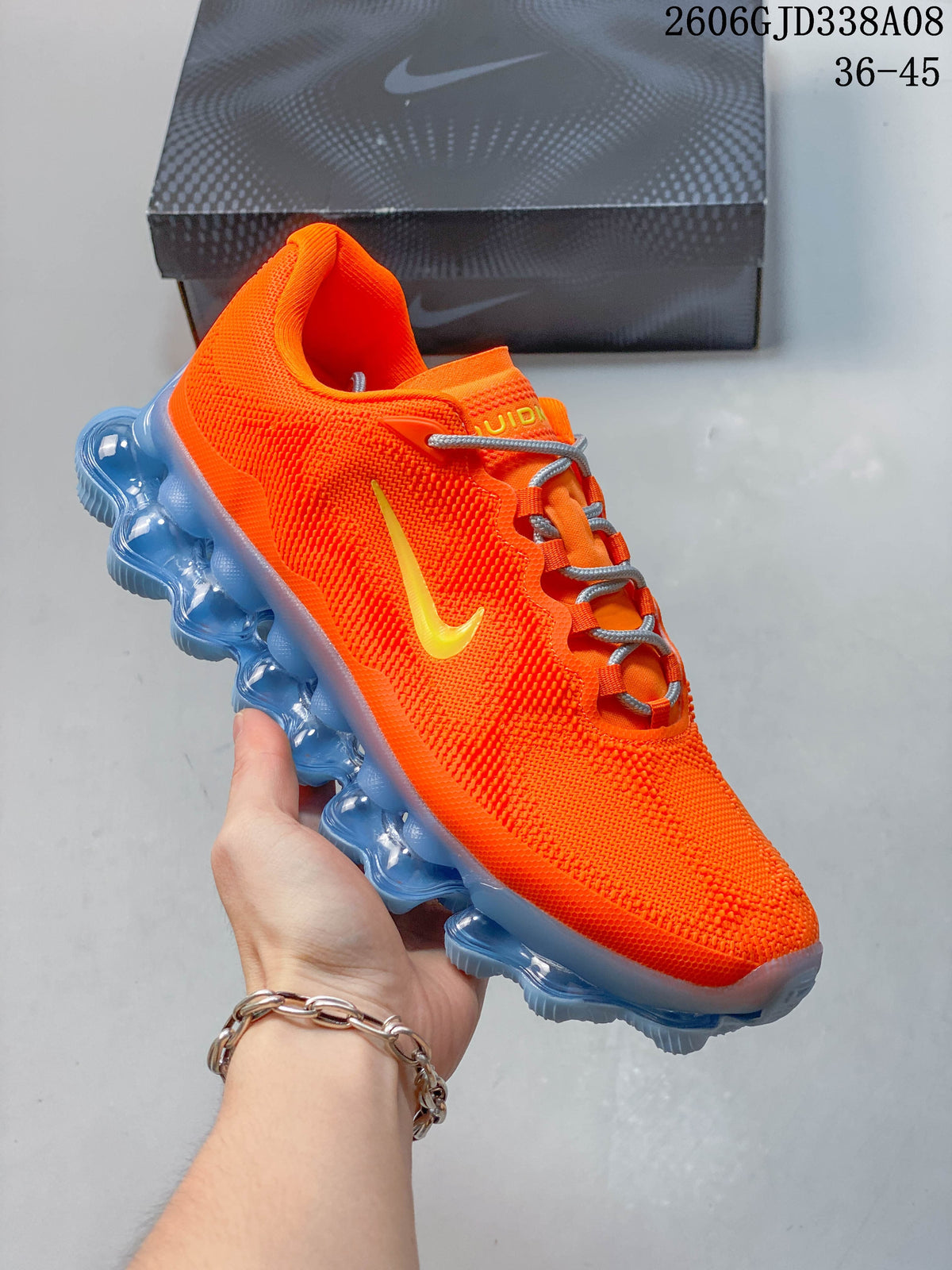 Angled side view of the orange shoe with a yellow logo and translucent blue sole.