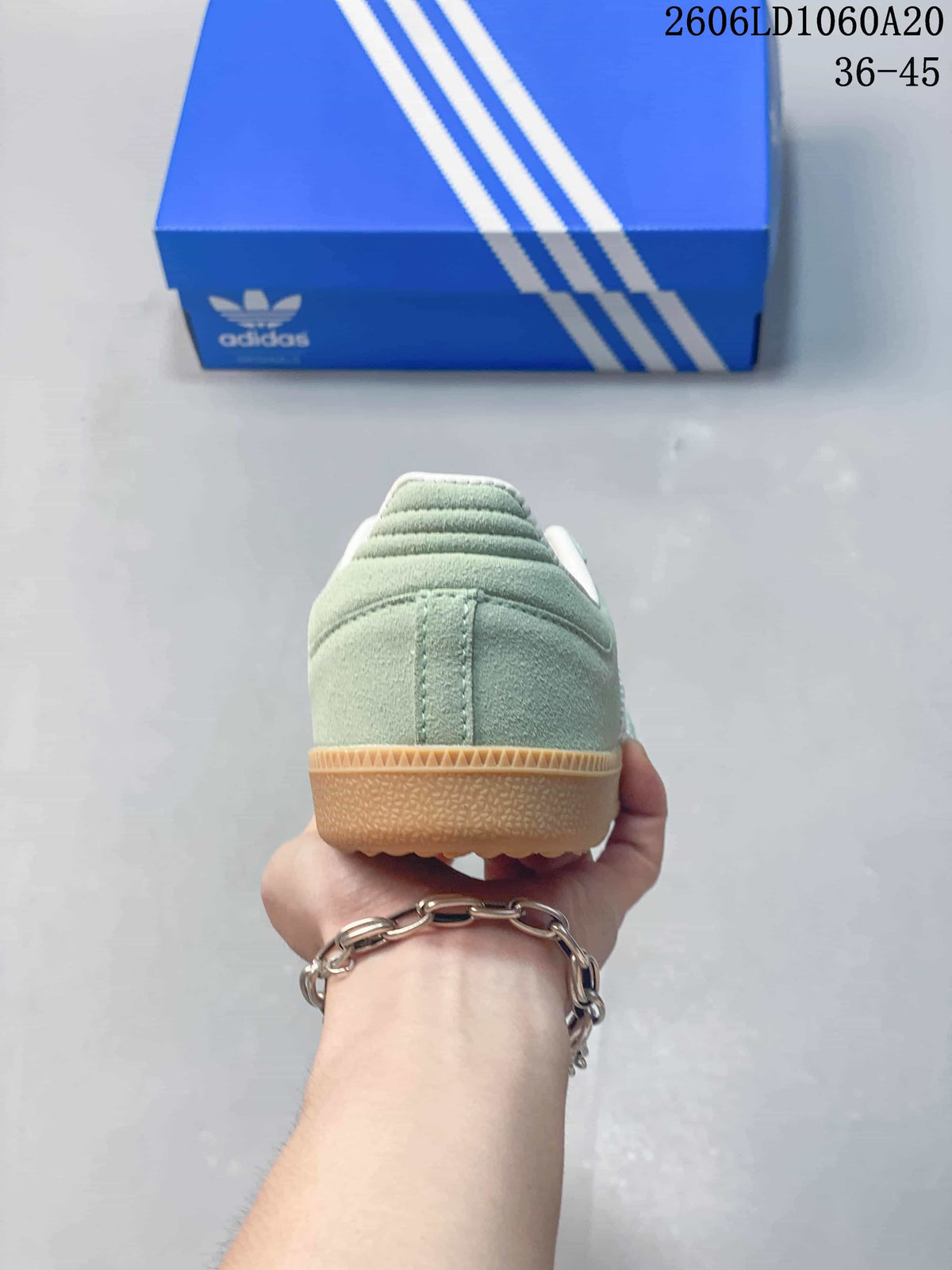 Rear view of a pale green sneaker showing the heel and gum-colored sole.