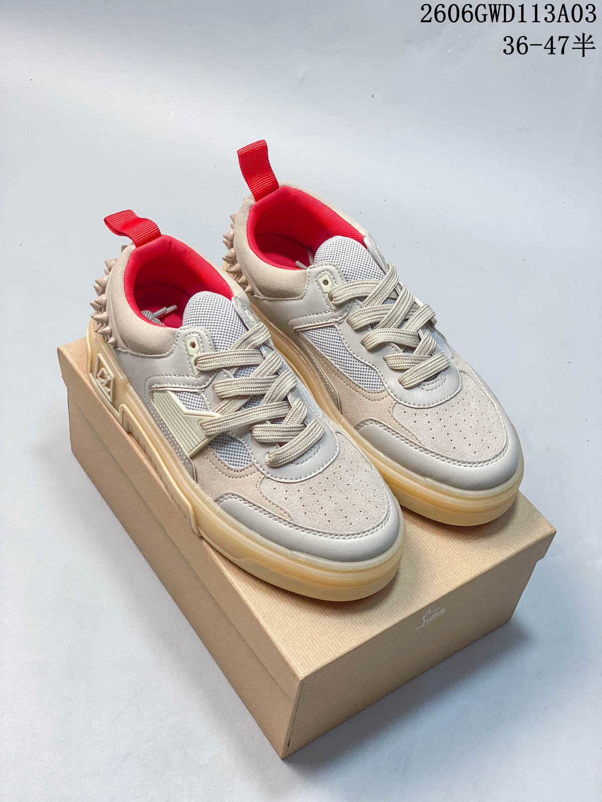 Pair of beige and light gray Astroloubi low-top sneakers with red lining, heel tabs, and decorative heel studs