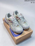 Pair of ASICS Gel-Kahana 8 sneakers in pale gray-white, cream, and burgundy, shown on a shoe box.