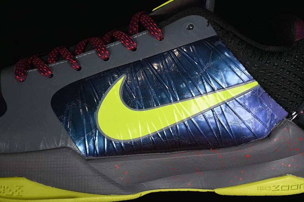 Side close-up of the glossy blue-purple panel and yellow Swoosh