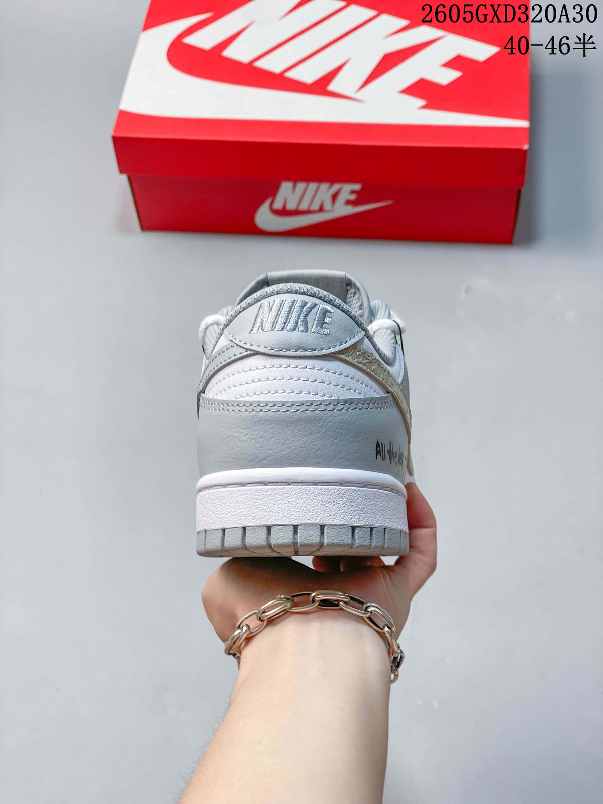 Rear view of a white and gray Nike Dunk sneaker with a branded heel tab.