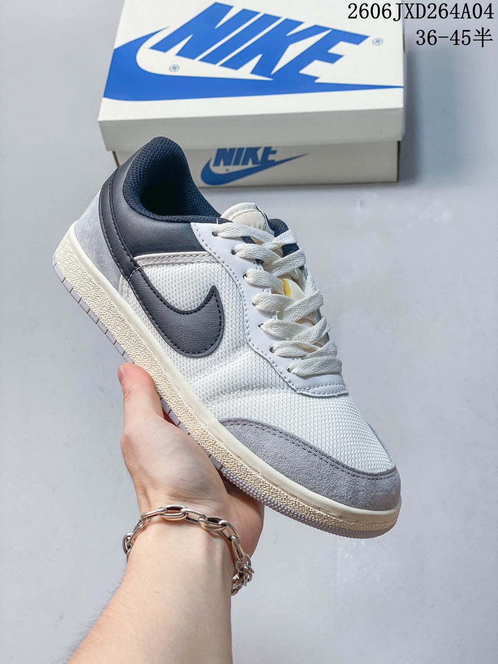 White low-top sneaker with dark gray accents, textured panels, and a light-colored sole