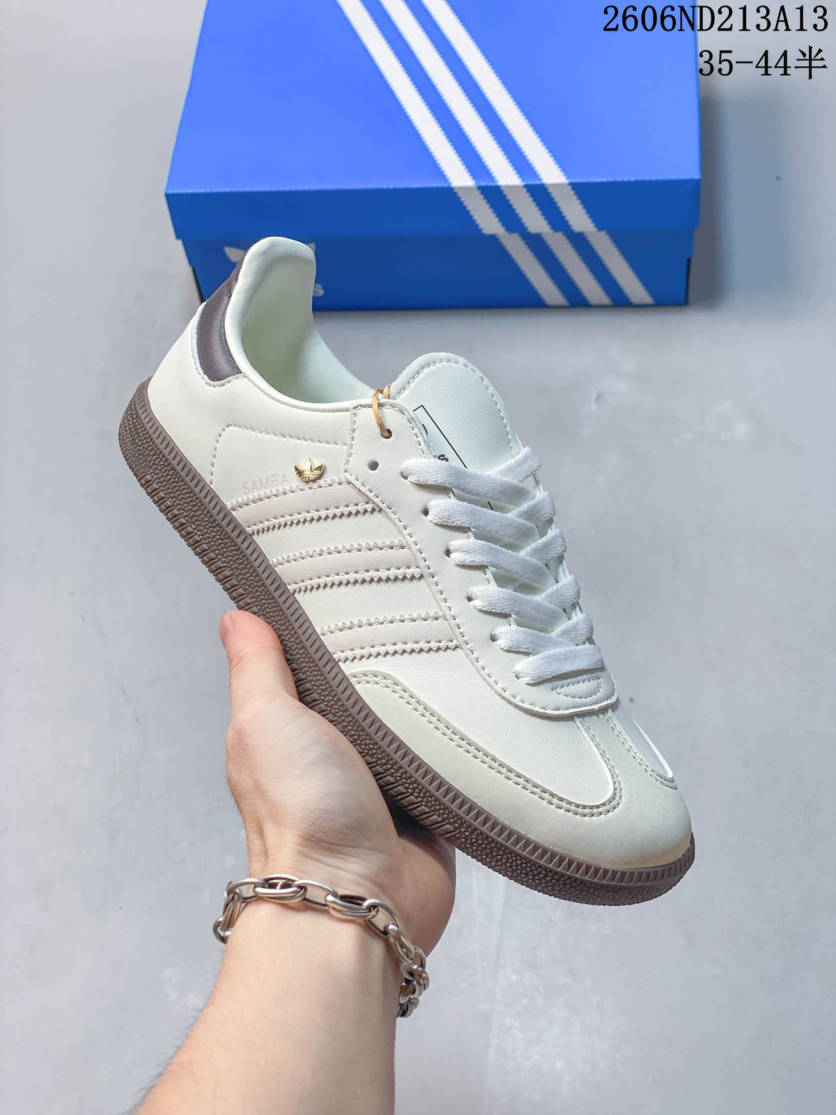 Angled side view of a white adidas Samba OG sneaker with grey stripes and heel panel