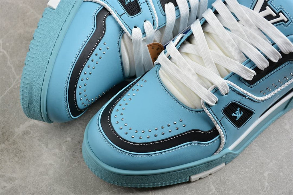 Close-up of the sneaker toe with blue panels, navy trim, white stitching, and stud accents