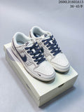 Pair of cream and navy low-top Nike Dunk sneakers with patterned side panels, displayed on a box.