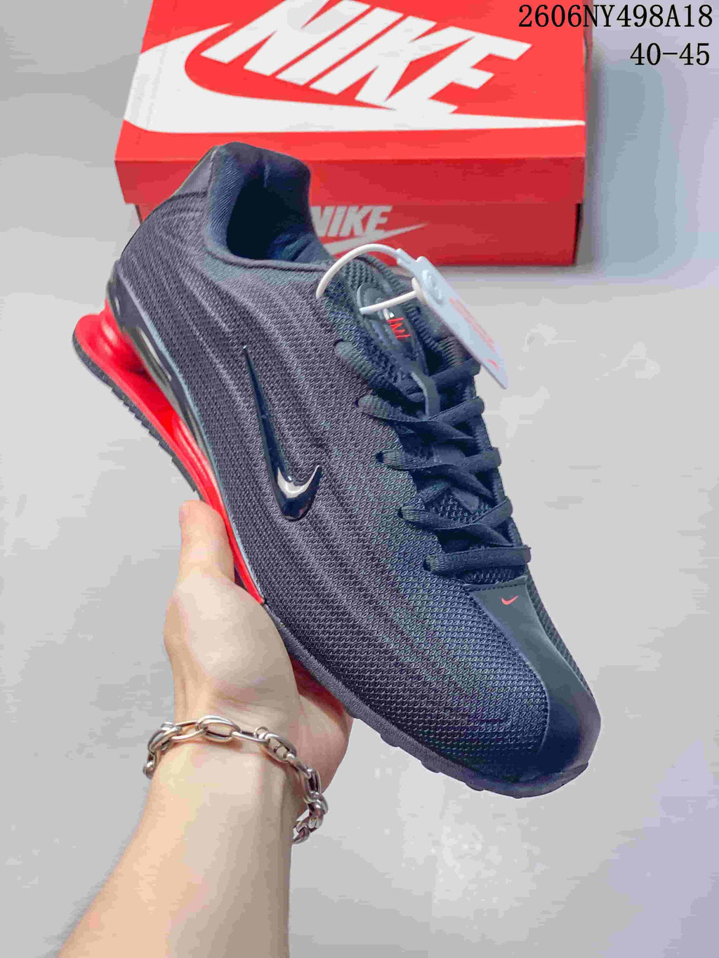 Angled side view of a charcoal Nike Shox TL sneaker with red detailing.