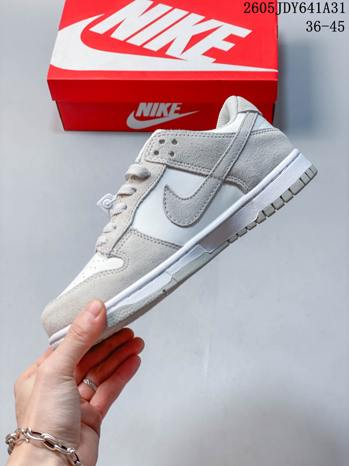 Side profile of a white and light grey low-top sneaker with a Swoosh detail