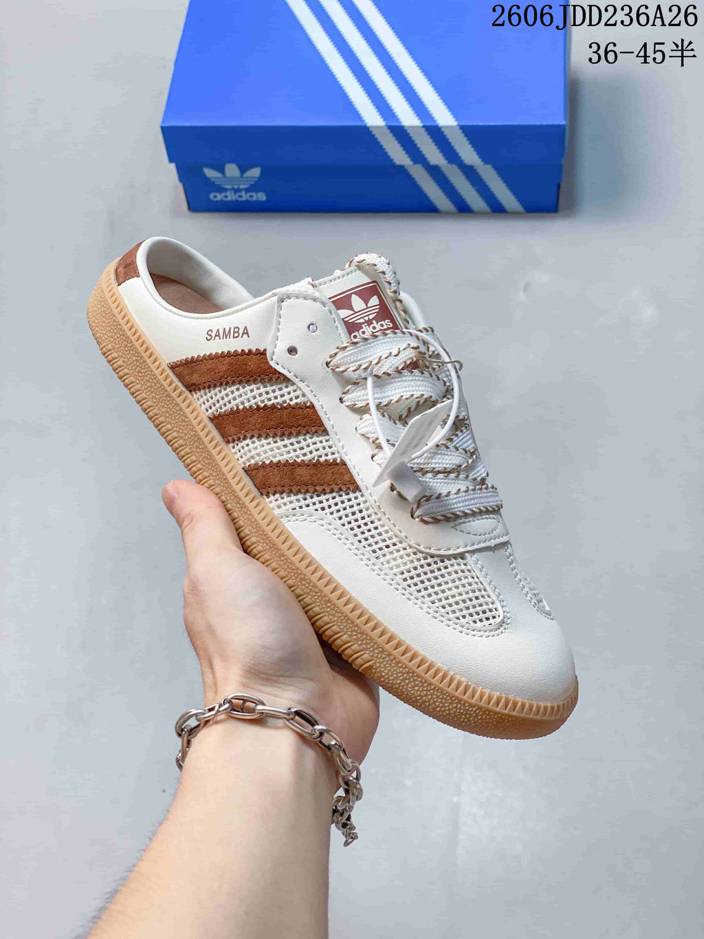 Side view of a cream Samba-style sneaker with brown stripes, mesh panels, and an open heel