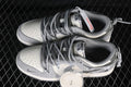 Pair of grey and off-white low-top sneakers viewed from above, showing cord-style laces and an extra set of light-colored laces.