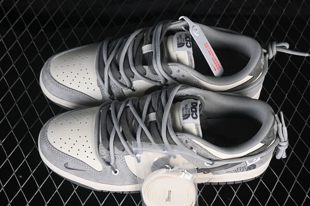 Pair of grey and off-white low-top sneakers viewed from above, showing cord-style laces and an extra set of light-colored laces.