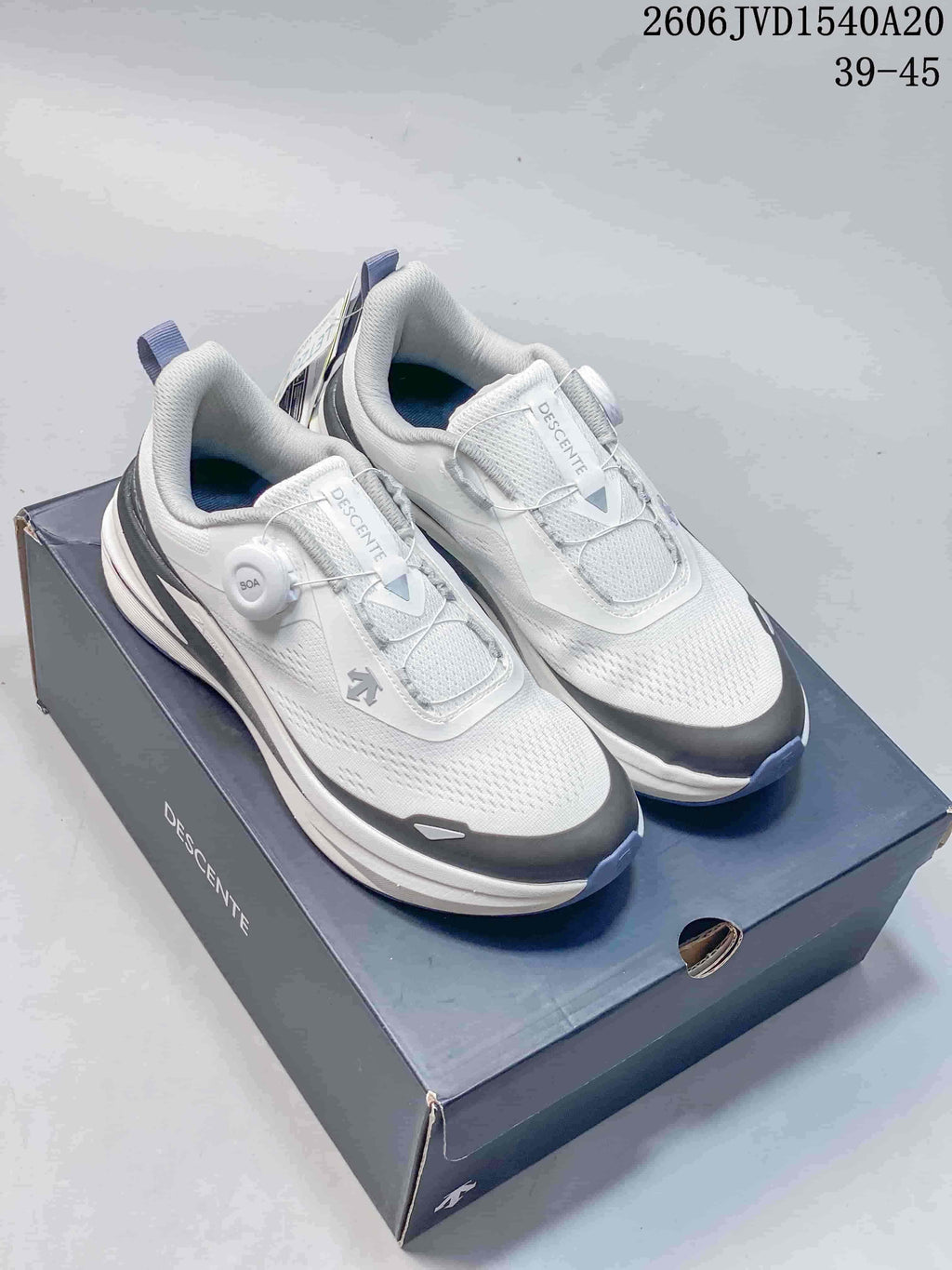 Pair of white and gray DESCENTE SNOW RIDE GTX sneakers with dial-style closures on a shoebox