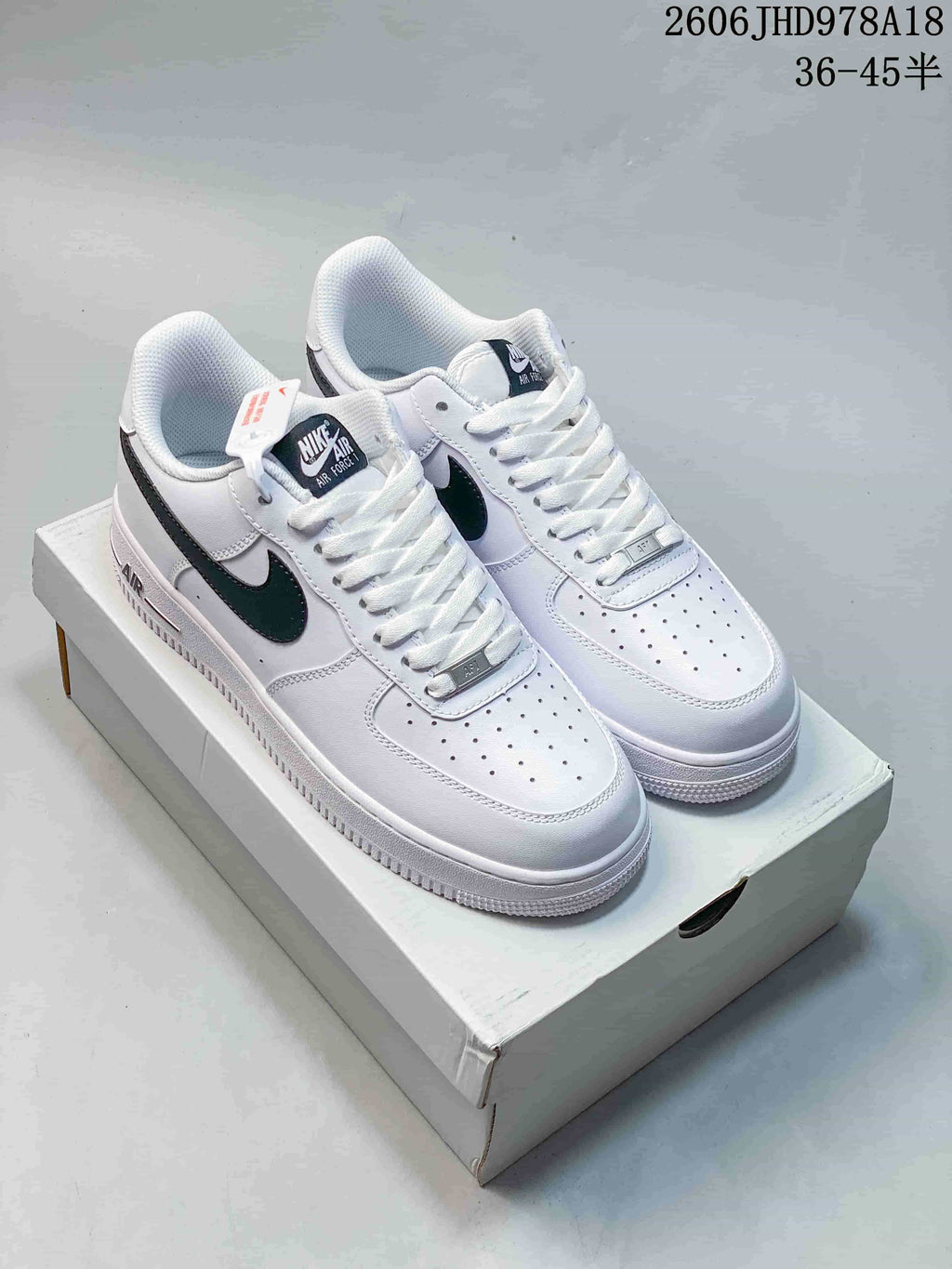 Pair of white Nike Air Force 1 low-top sneakers with black Swoosh accents on a shoebox
