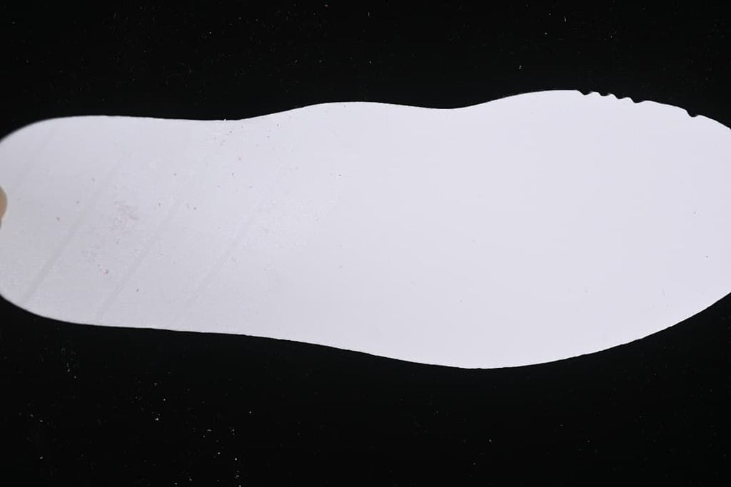 White shoe-shaped piece photographed against a dark background