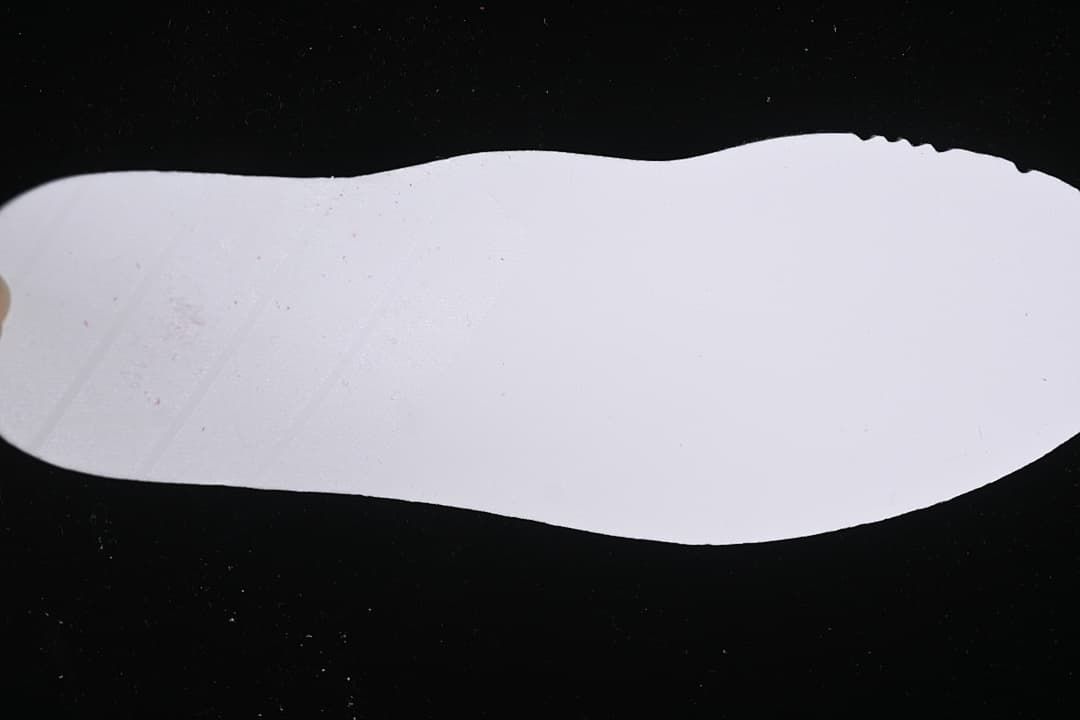 White shoe-shaped piece photographed against a dark background
