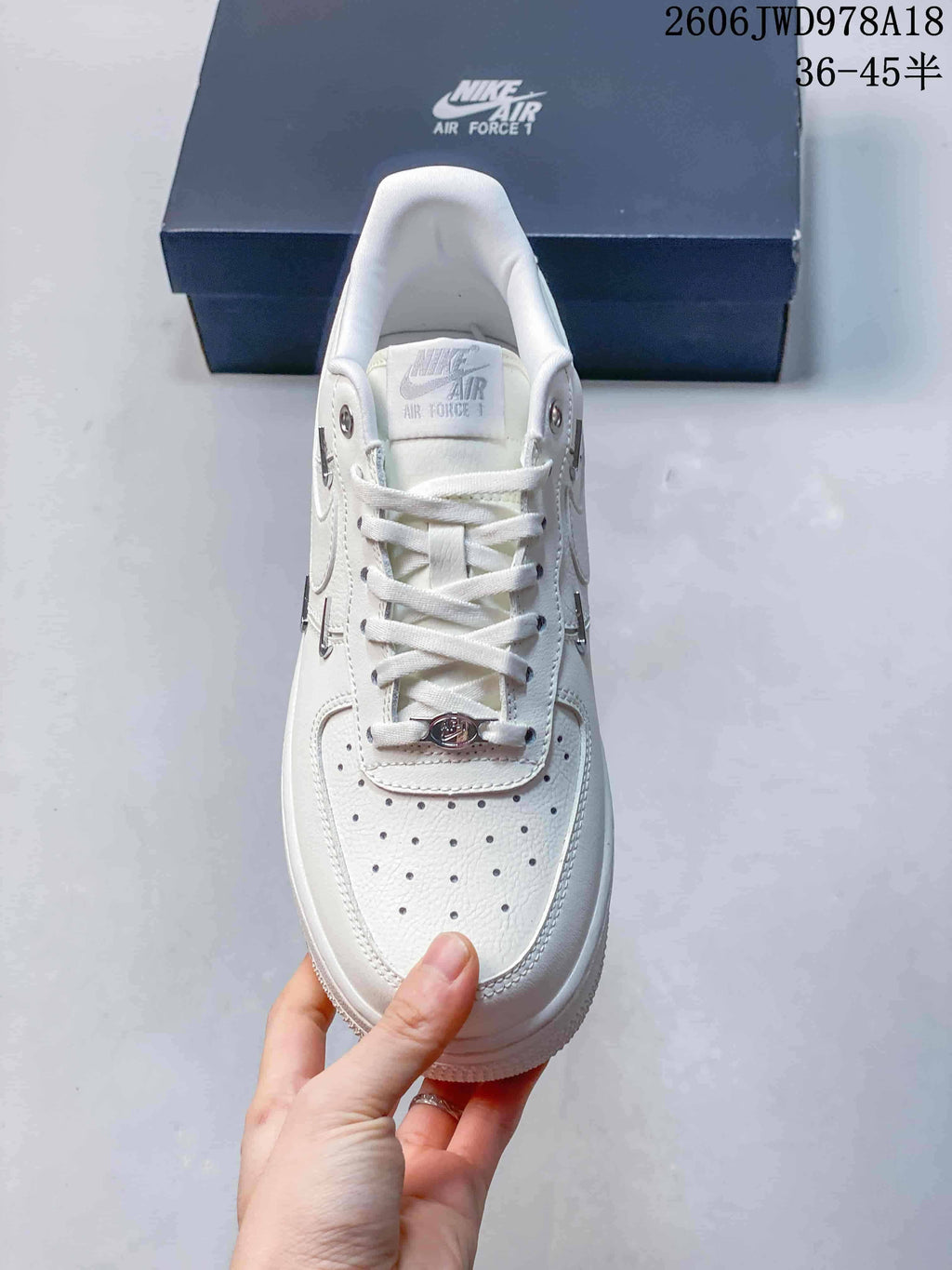 Top view of the white sneaker showing perforations on the toe and metallic lace detail.