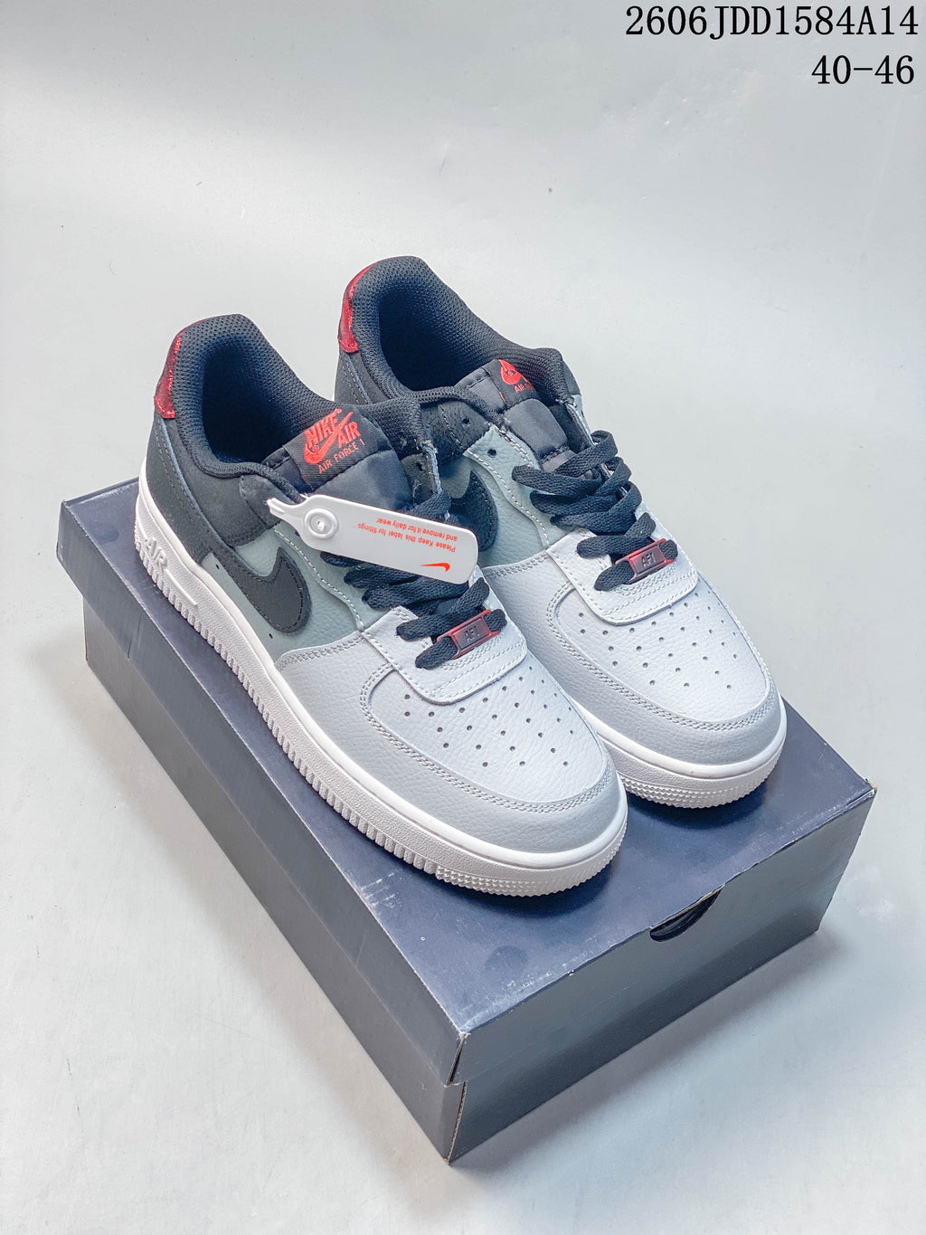 Pair of white and grey Nike Air Force 1 low-top sneakers with dark and red accents