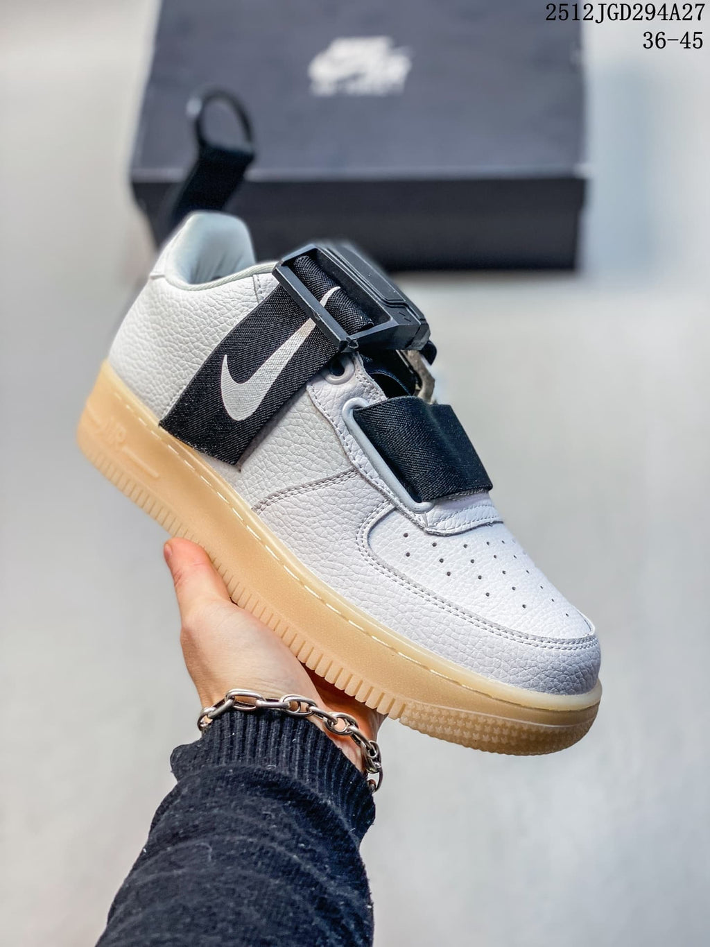 Angled view of the white sneaker with black straps and side logo