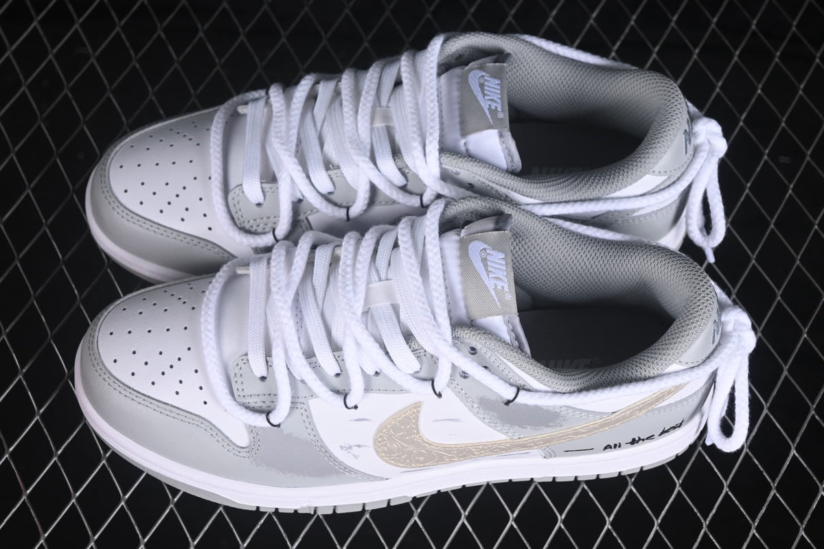 Top and side view of white and grey low-top sneakers with perforated toe boxes, white laces, and gold Swoosh accents.