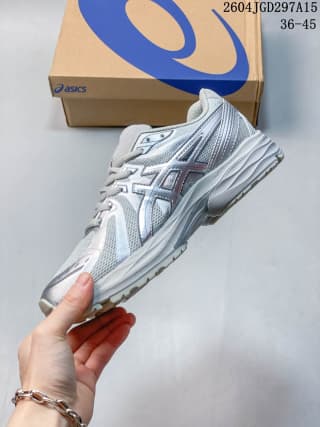 Side view of a white and silver ASICS Gel-Flux CN sneaker held in front of its branded shoe box.