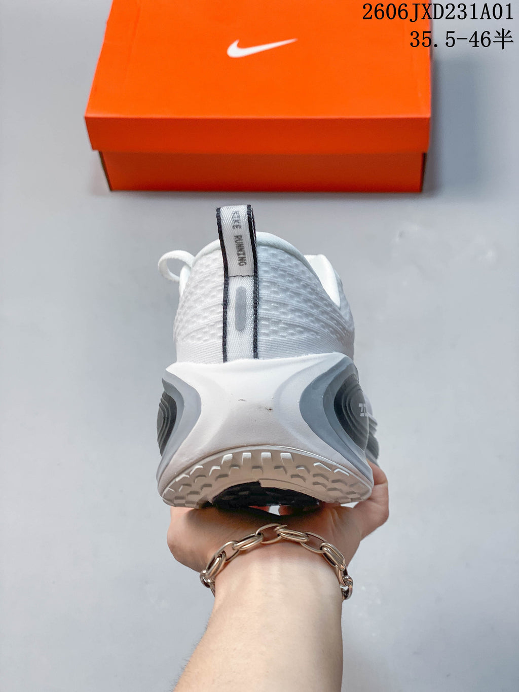 Rear view of a white Nike Vomero Plus shoe with gray heel details.