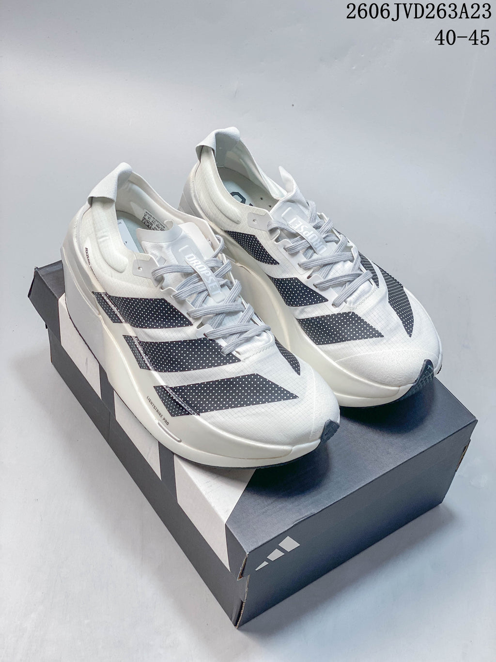 White Adidas Adizero Dropset Elite shoes with dark three-stripe detailing displayed on a shoebox; image overlay states sizes 40–45.