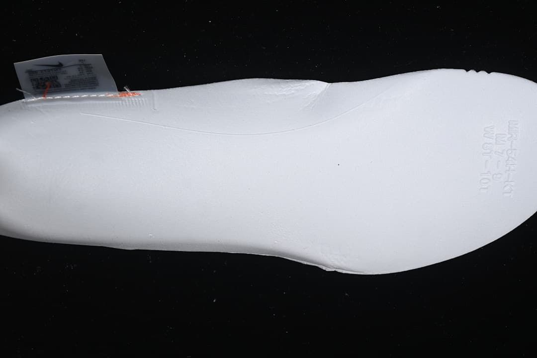 Underside view of a white shoe with faint embossed markings.