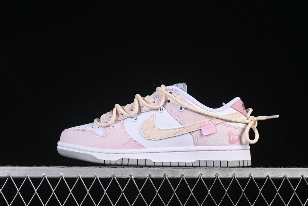 Side view of pale pink and white Nike SB Dunk Low sneakers with cream laces